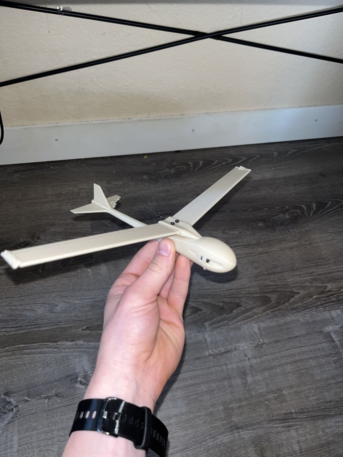 Complete white 3D-printed glider held above a dark floor